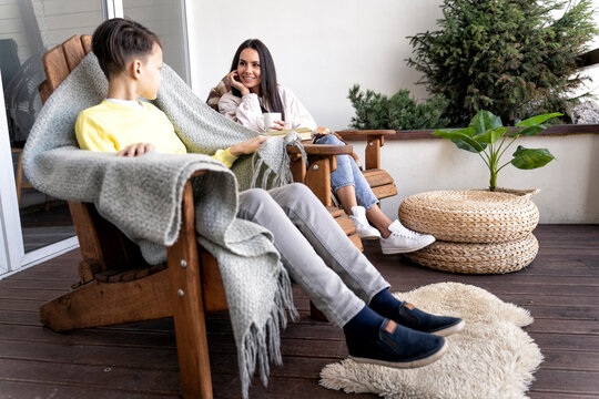 Mother looking at son while sitting on chair on balcony