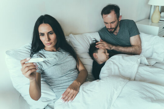 Woman measuring temperature while father taking care of son at home