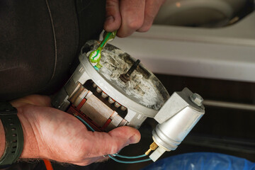  Repair Service Worker. Repairman is removing scale on the pomp of old dishwasher machine. Repair...