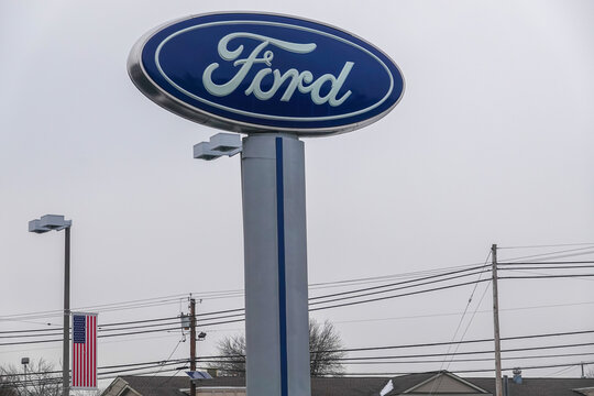 The Ford Motor Company Logo As Seen On A Tall Sign At A Car Dealership. Ford's Headquarters Are In Dearborn, Michigan