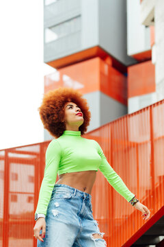 Afro hairstyle wearing crop top looking up while standing by railing