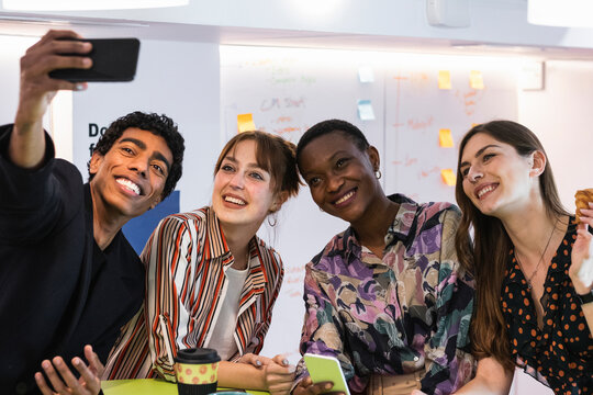 Cheerful business people taking selfie through smart phone at office