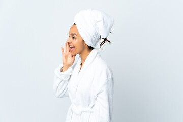 Young woman in bathrobe over isolated white background shouting with mouth wide open to the side