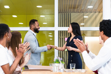 Colleagues clapping for entrepreneurs doing handshake in meeting at office