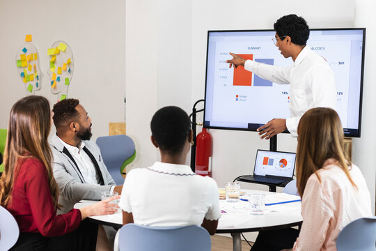 Businessman explaining plan over television to colleagues at office