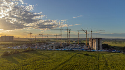 construction equipment, cranes build a house against the sunset