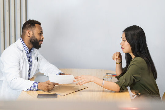 Male doctor holding paper while explaining patient at clinic