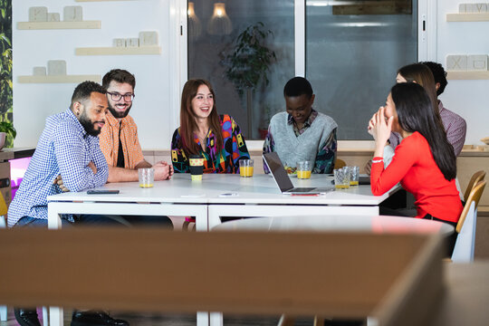 Multi ethnic coworkers smiling while sitting at table in cafeteria
