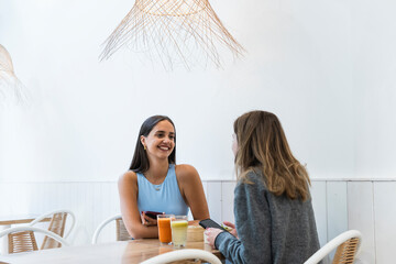 Female friends talking to each other while sitting at cafe