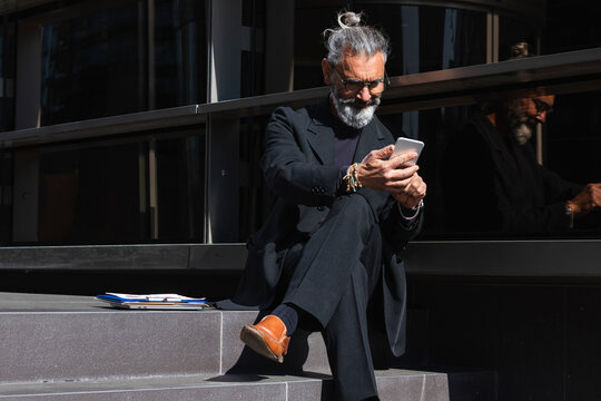 Male entrepreneur working on mobile phone while sitting on steps by building