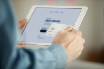 Male freelancer paying through credit card while using digital tablet in office