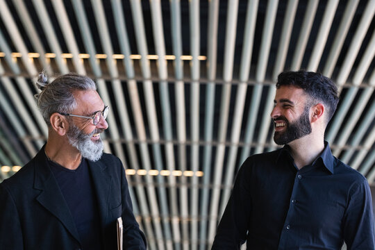 Happy male professionals smiling while looking at each other