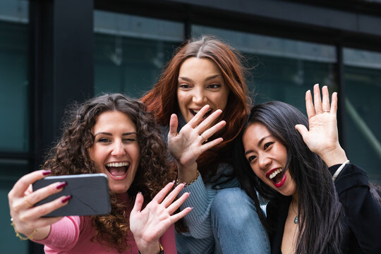 Cheerful friends waving hand to video call on mobile phone