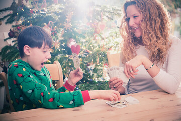 Smiling mother looking at son while playing cards during Christmas at home