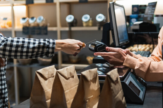 Female owner with card reader receiving payment from customer at supermarket 
