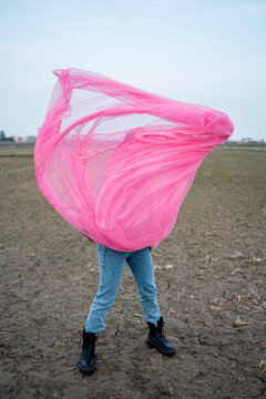Woman playing with pink tulle net on dirt field