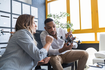 Businessman explaining drone model to female colleague in coworking office