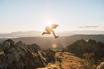 Sportsman jumping on mountain during sunny day