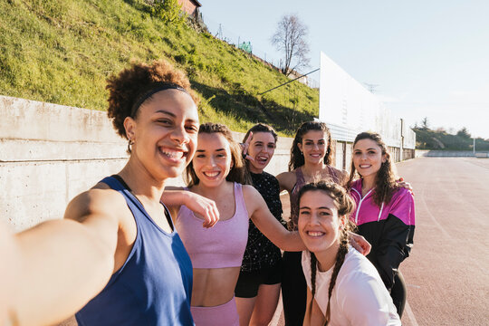 Smiling female athletes talking selfie on training ground