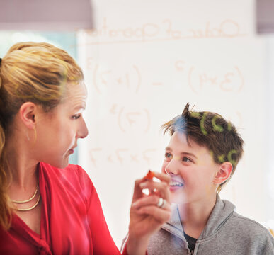 Mother looking at smiling son while teaching mathematics on glass