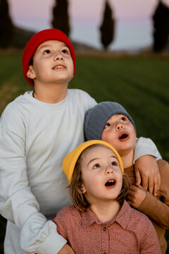 Brothers and sister wearing knit hat with mouth open looking up
