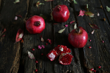 Ripe pomegranates on a wooden table. Autumn still life with pomegranates on a dark background. Country style.