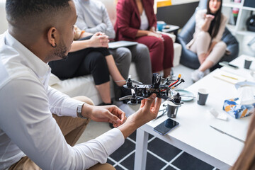African male engineer discussing over drone with colleagues during meeting in coworking office