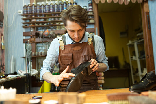 Male cobbler examining shoe at workshop - Powered by Adobe