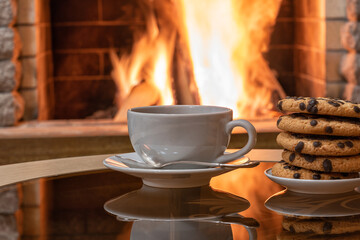 Cozy Fireplace, white cup of tea and cookies on a table.