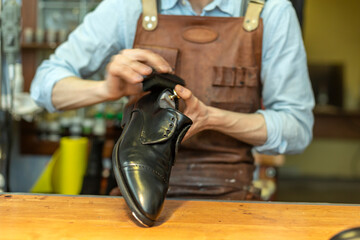 Male cobbler holding shoe while polishing at workshop