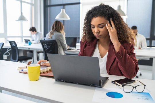 Confused female professional working with male and female colleagues in background at office