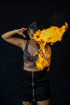 Young woman playing with fire against black background