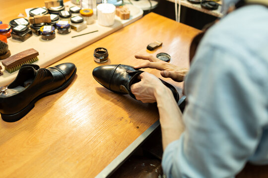 Male craftsperson applying polish on shoe in workshop