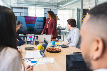 Male and female professionals discussing during meeting in board room at coworking office