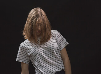 Girl with a long bob haircut in a T-shirt and jeans on a dark background