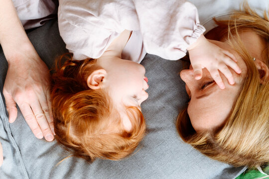 Daughter stroking mother while lying on bed at home