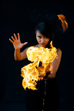 Female fire dancer with fire against black background