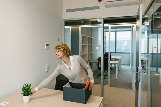Mature businesswoman arranging desk in office