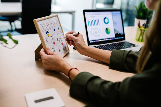 Woman making reminder table by laptop on desk at office