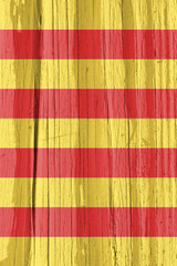 Fototapeta na wymiar Catalan flag on dry wooden surface, cracked with age. Vertical background, wallpaper or backdrop with symbol of Catalonia. It seems to flutter in the wind. Hard sunlight with shadows on old wood
