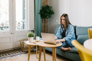 Businesswoman smiling while looking at laptop during video conference at home office