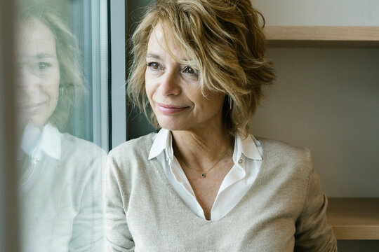 Mature businesswoman contemplating while looking through window at office