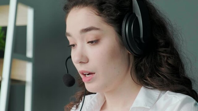 Support hotline worker, girl puts on her headphones and starts talking to the clients, work remotly, from home office, or distance learning.