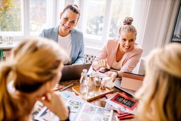 Smiling female event planners and customers discussing at office