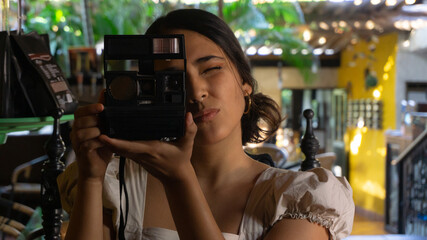 Latin woman taking photos in a restaurant with old camera