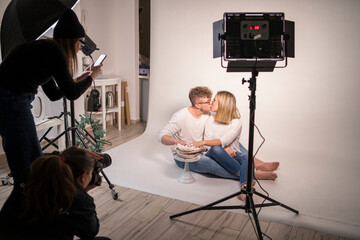 Couple with cake kissing while doing photo shoot in studio
