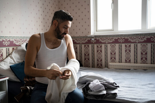 Businessman in vest getting dressed while sitting at home