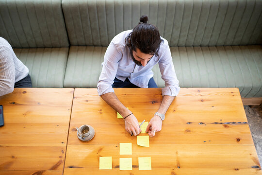 Businessman sticking adhesive note on table while working in office