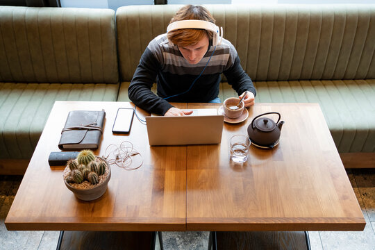 Businessman using laptop by teacup while sitting at desk in office