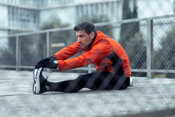 Athletic man doing stretching exercise in park
